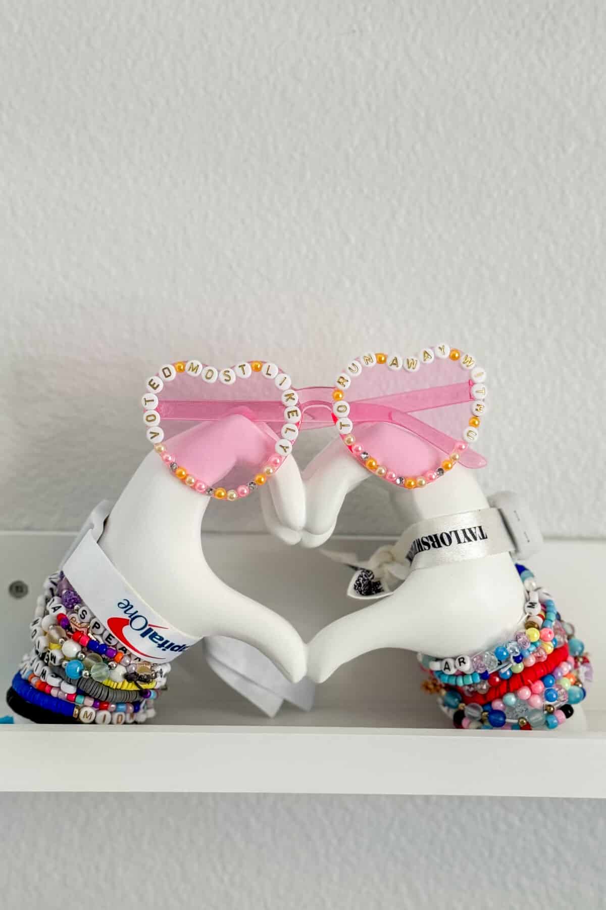 heart hand statue with friendship bracelets and heart sunglasses on top.