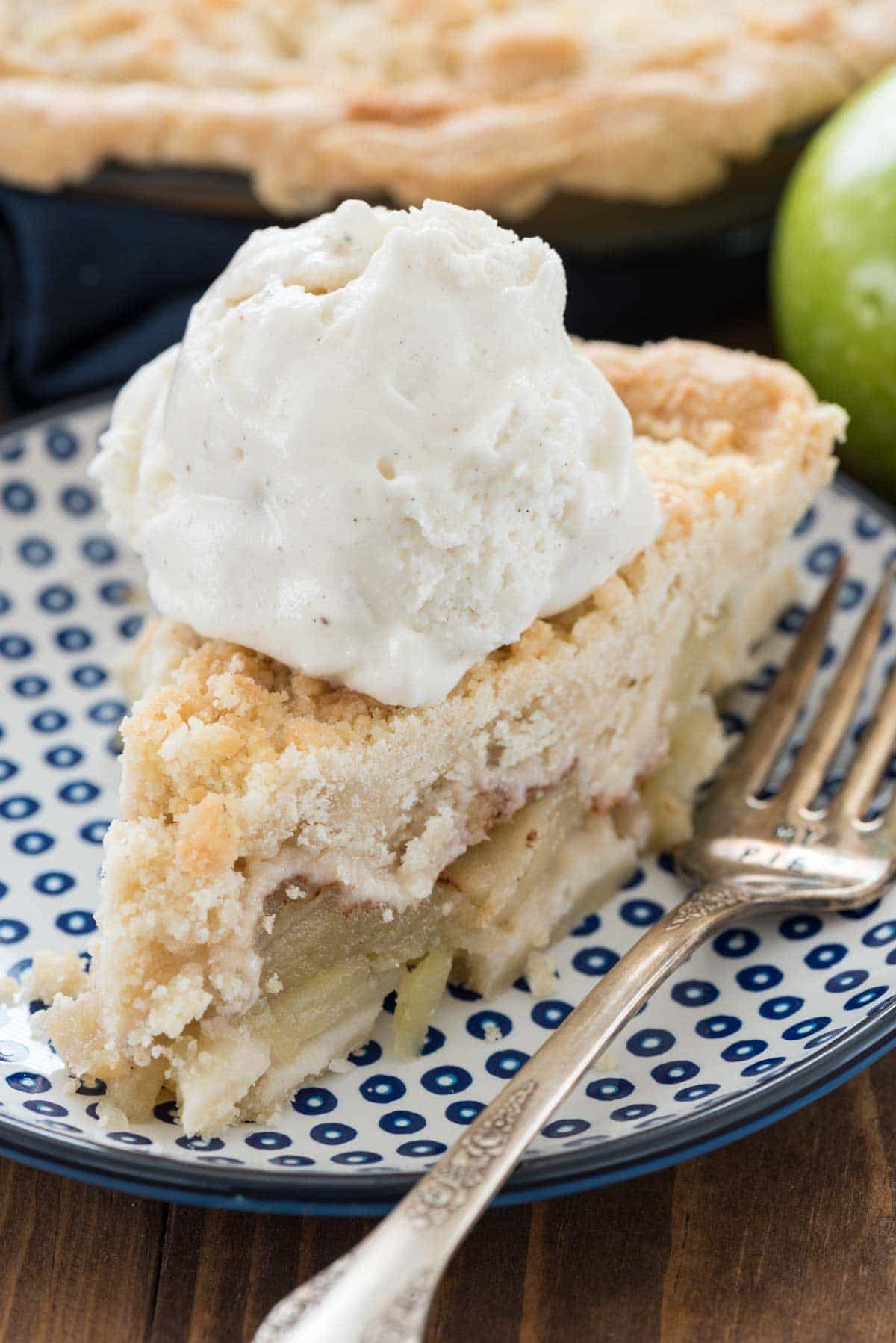 Crumb Apple Pie slice with vanilla ice cream scoop on top.