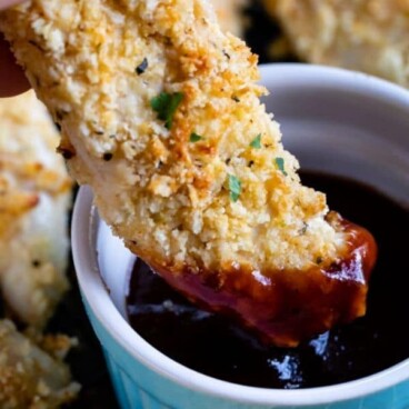 hand dipping chicken tender in barbecue sauce with words on photo