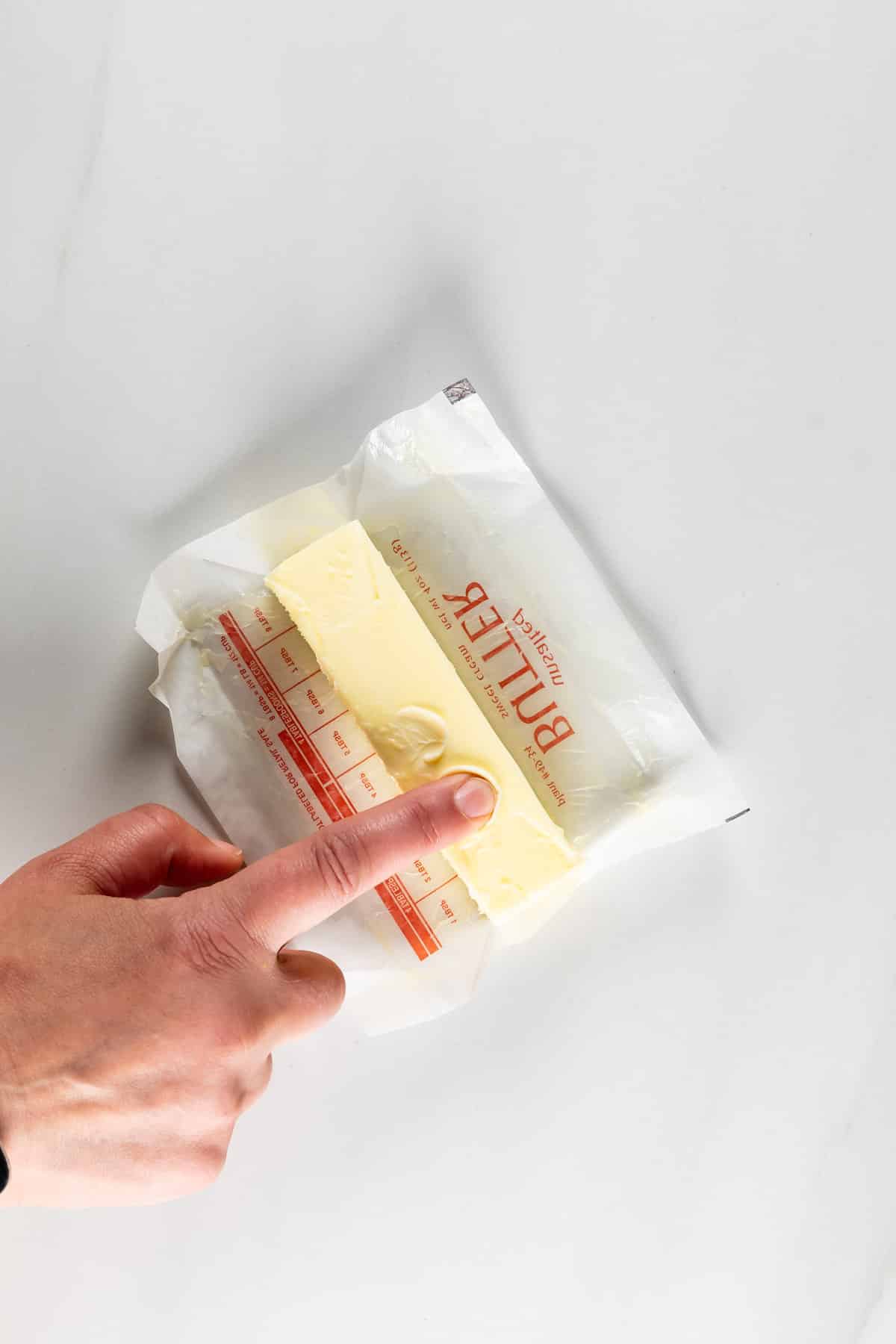 finger pressing into butter stick