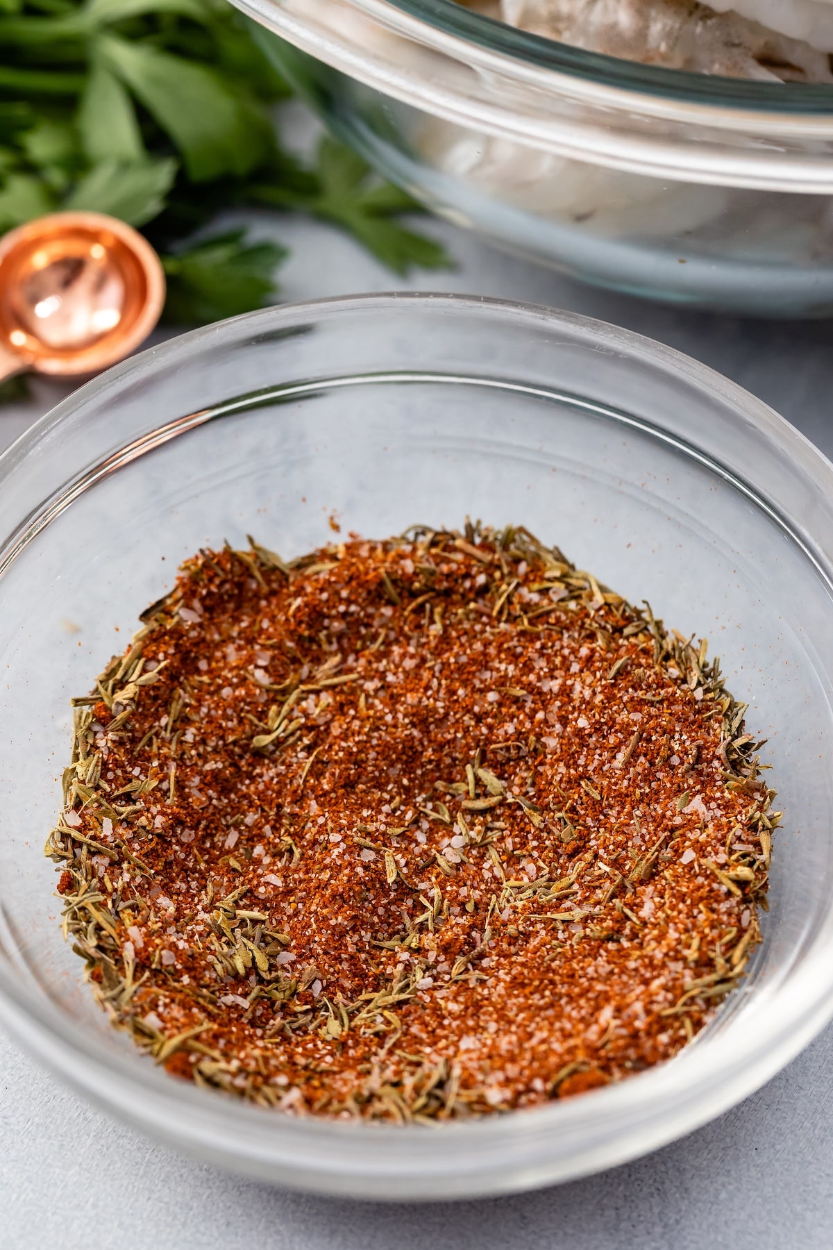 spices in clear bowl with herbs behind.