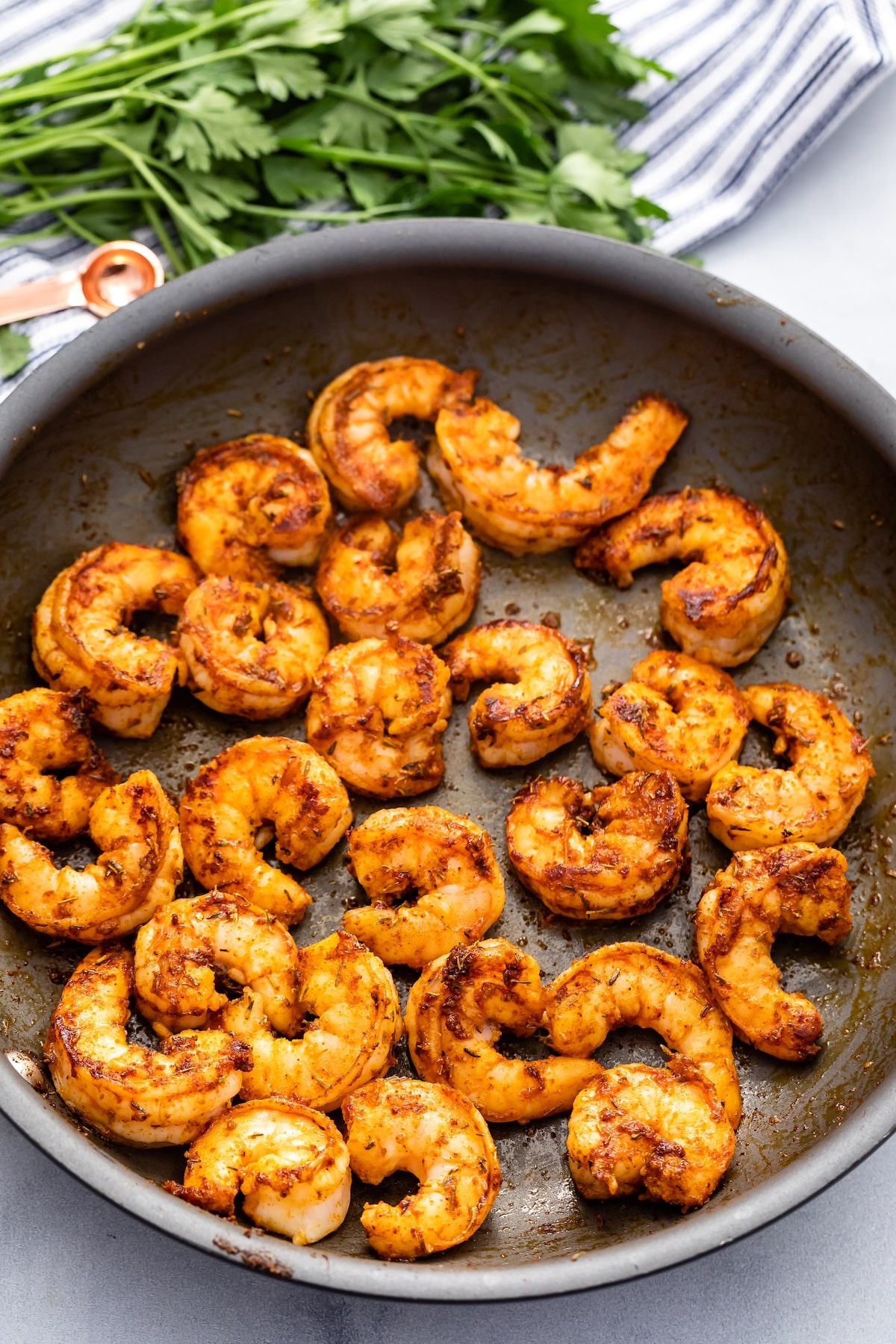 shrimp with cajun seasoning in nonstick frying pan.