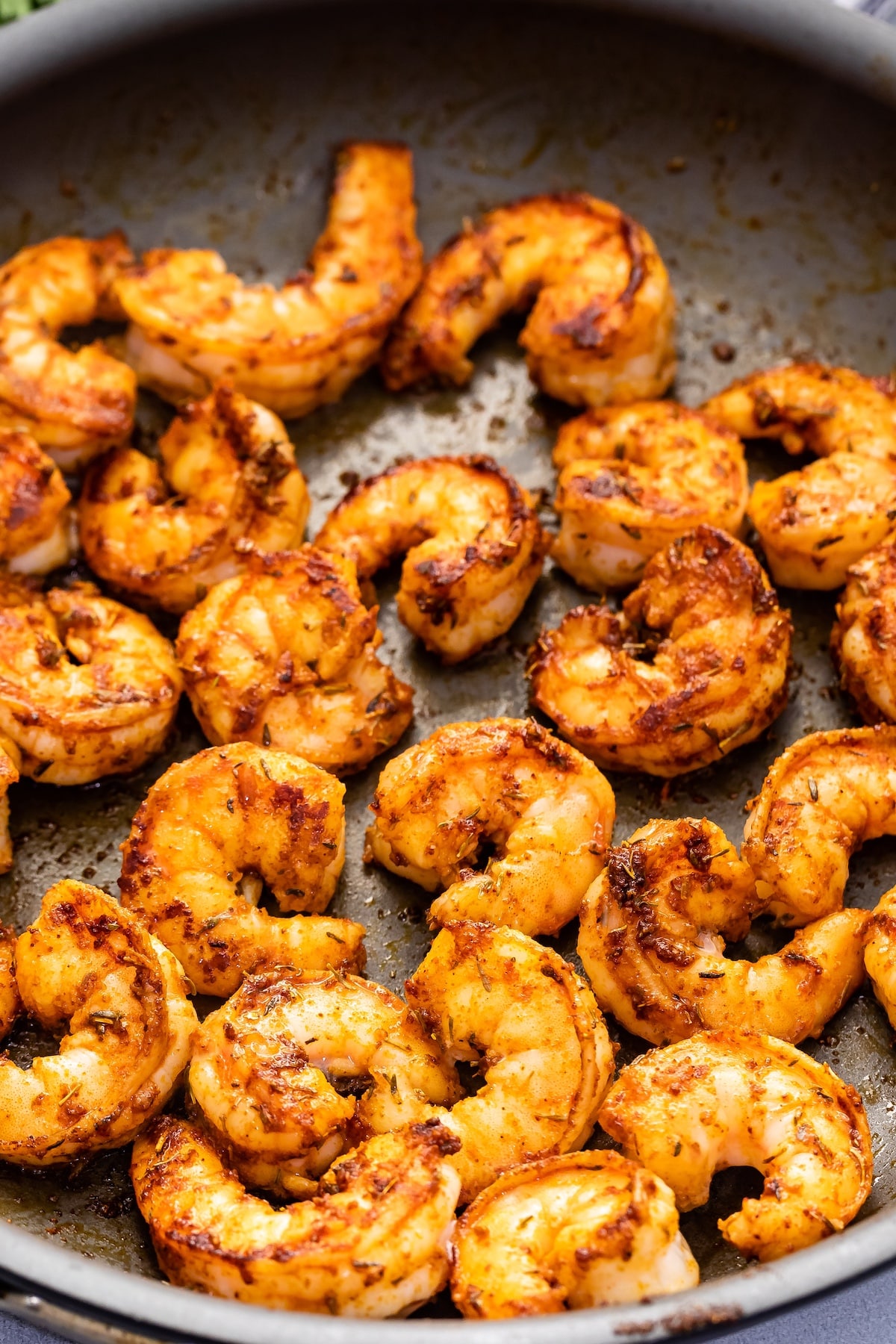 shrimp with cajun seasoning in nonstick frying pan.