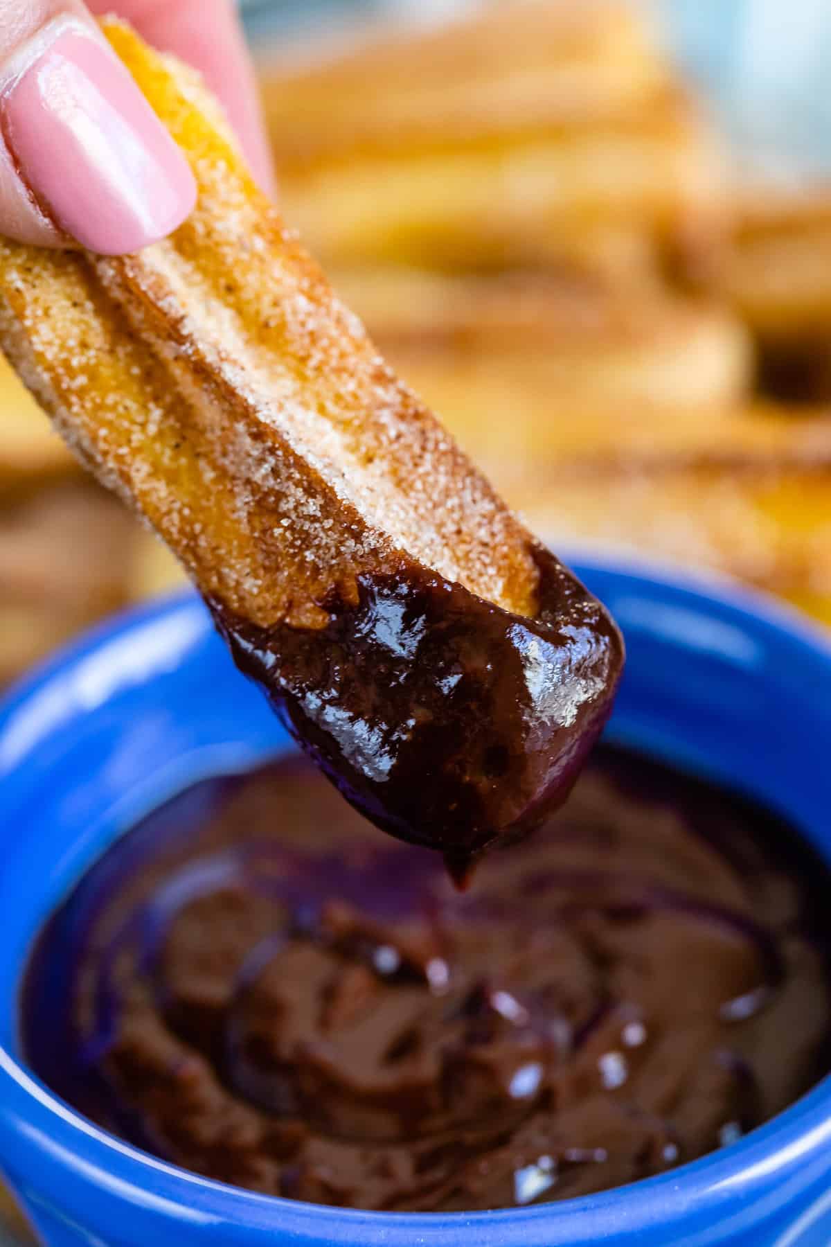 churro being dipped in blue Bowl of ganache.