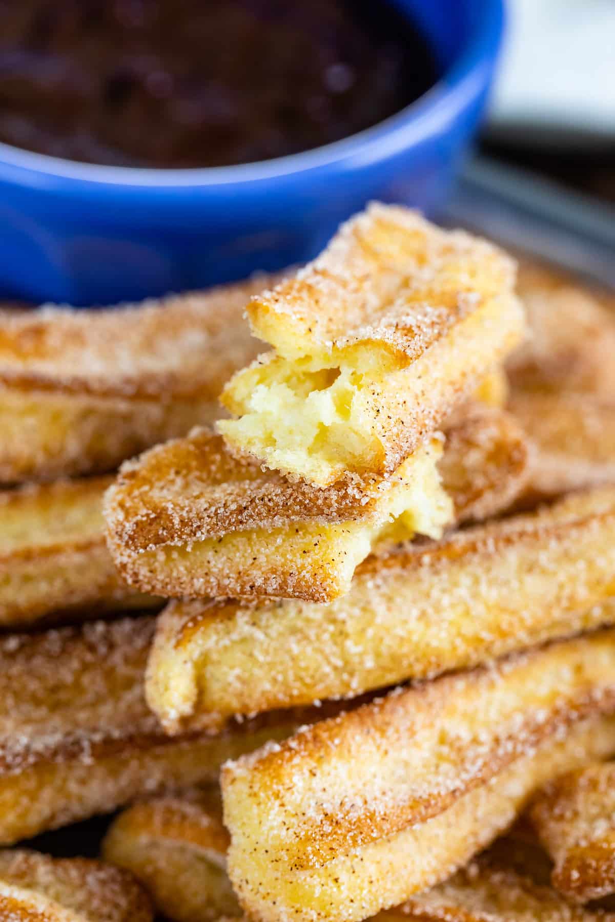stack of churros on tray with one cut in half.