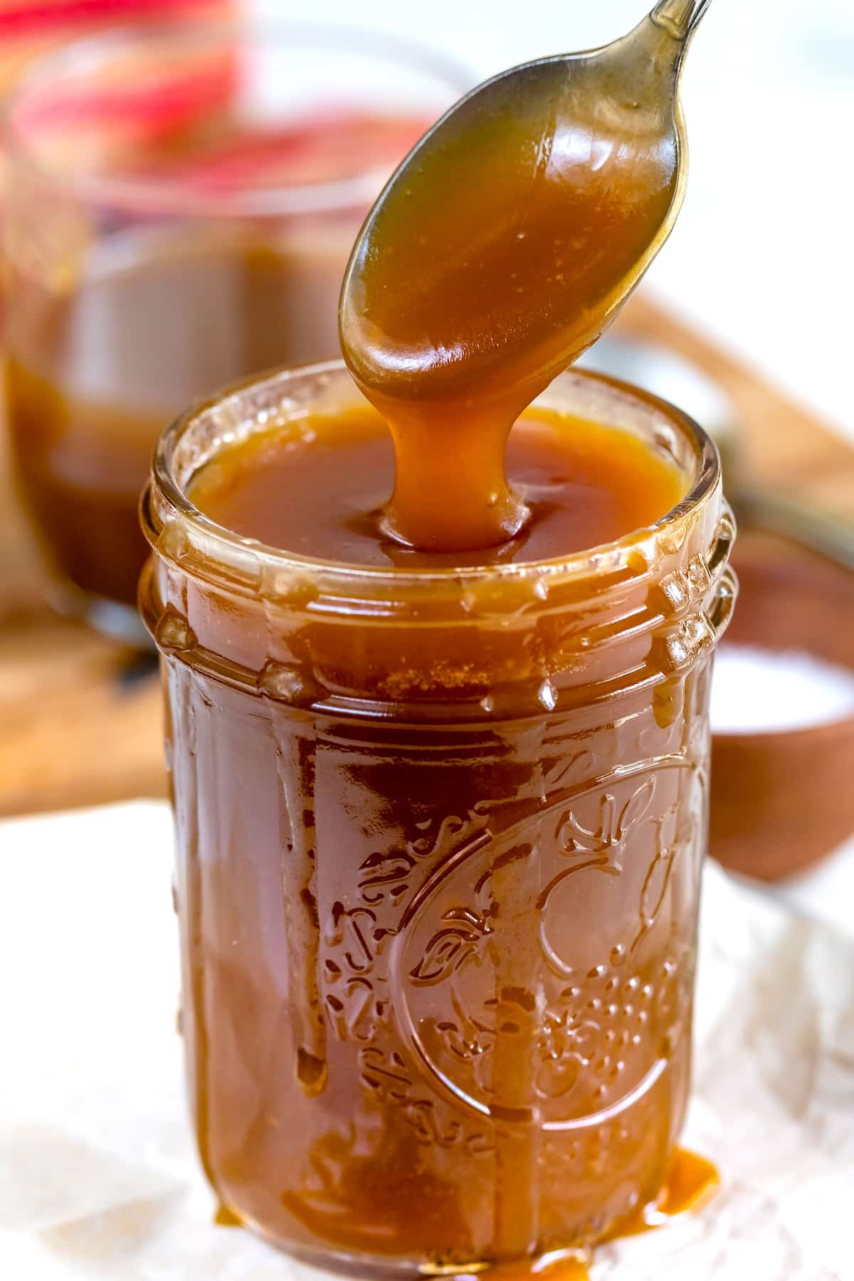 spoon above jar of caramel dripping caramel back into jar.