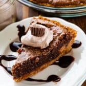 slice of chocolate pie with graham crust on white plate with hot fudge