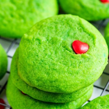 Grinch cookies staplade på ett metallstativ efter kylning med receptets titel överst på bilden