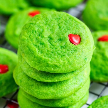 Close up photo of large stack of grinch cookies on a metal cooling rack