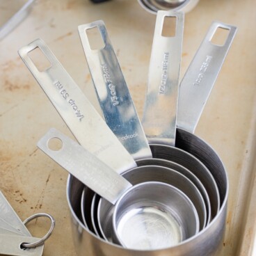 Close up shot of stainless steel measuring cups in corner of sheet pan