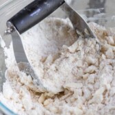 Crumble topping in a clear mixing bowl with pastry cutter