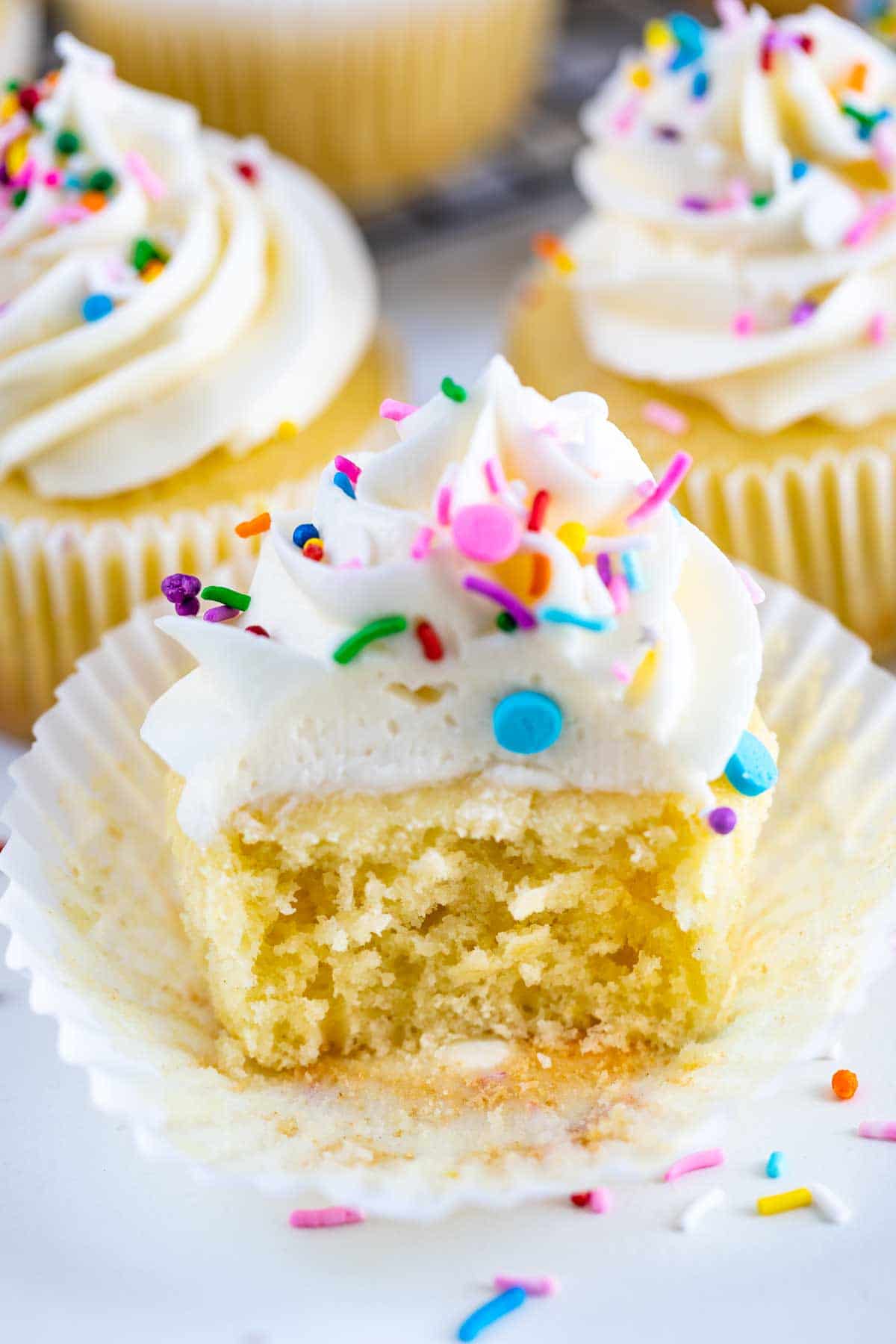 Perfect vanilla cupcake with vanilla buttercream cut in half to show fluffy inside