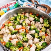 PAN WITH CHICKEN AND VEGETABLES ON WHITE BACKGROUND WITH BUTTER BEHIND