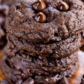 Stack of double chocolate chip cookies on a wood cutting board