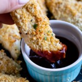 hand holding chicken tender dipping in BBQ sauce