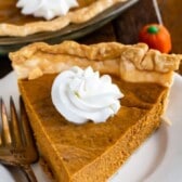 One slice of pumpkin pie on a white plate with fork