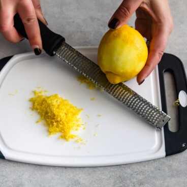 Overhead shot of lemon being zested over a cutting board