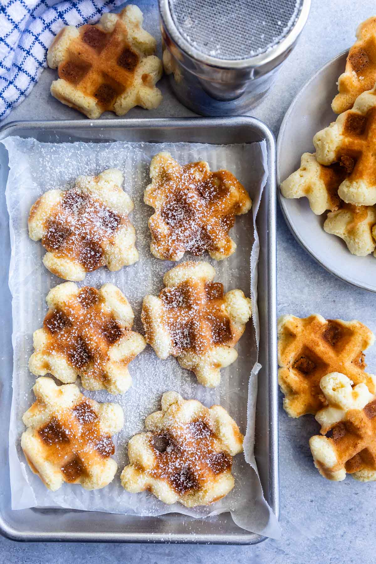 Overhead view of waffle cookies on a baking sheet and more around it
