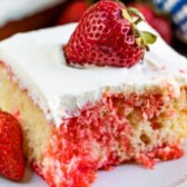 One piece of strawberry jello poke cake with strawberry on top