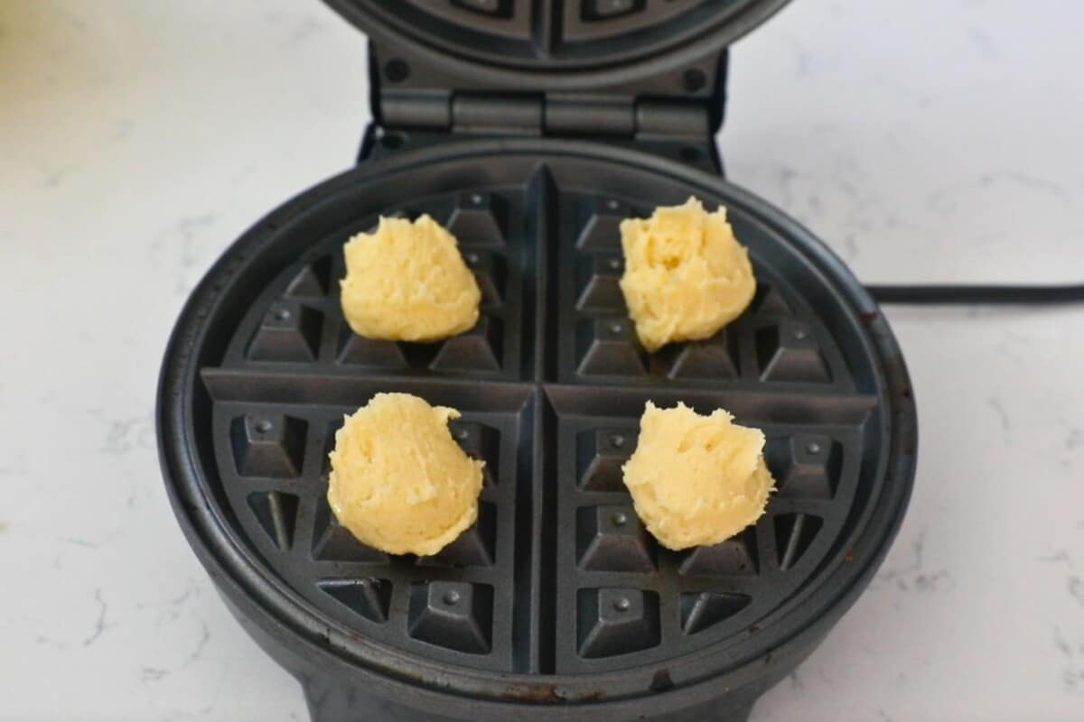 4 cookie dough balls in a round waffle maker.