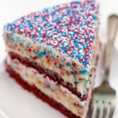 One slice of fireworks cake on a plate next to a silver fork