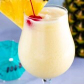 One pina colada with cherry and pineapple in top of glass