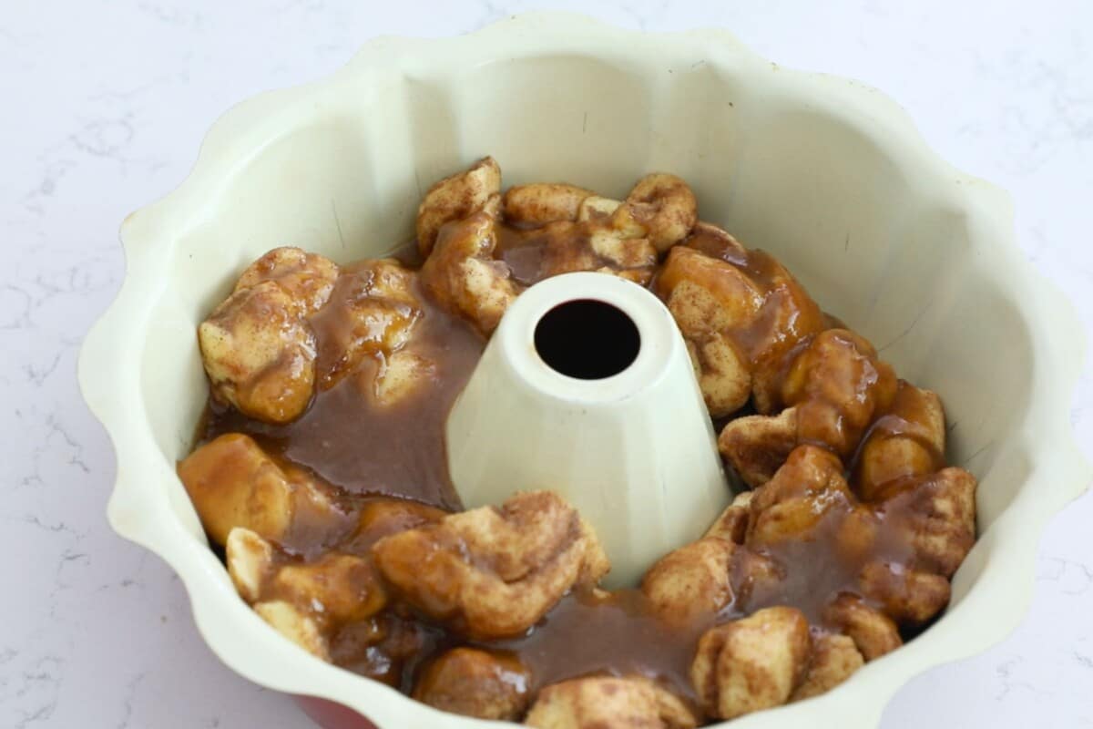 monkey bread unbaked in bundt pan with sauce.