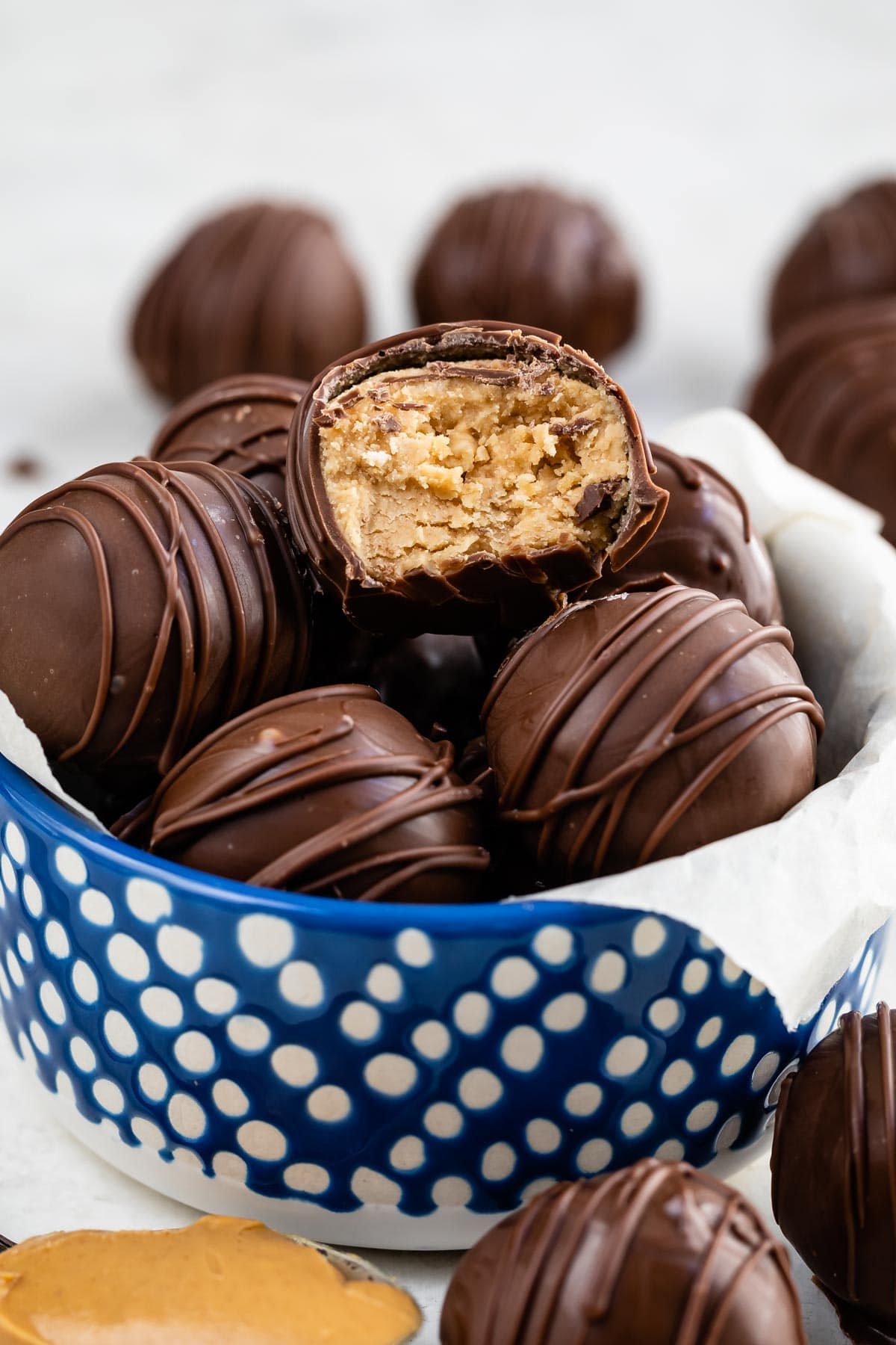 blue bowl with peanut butter balls inside and one cut in half