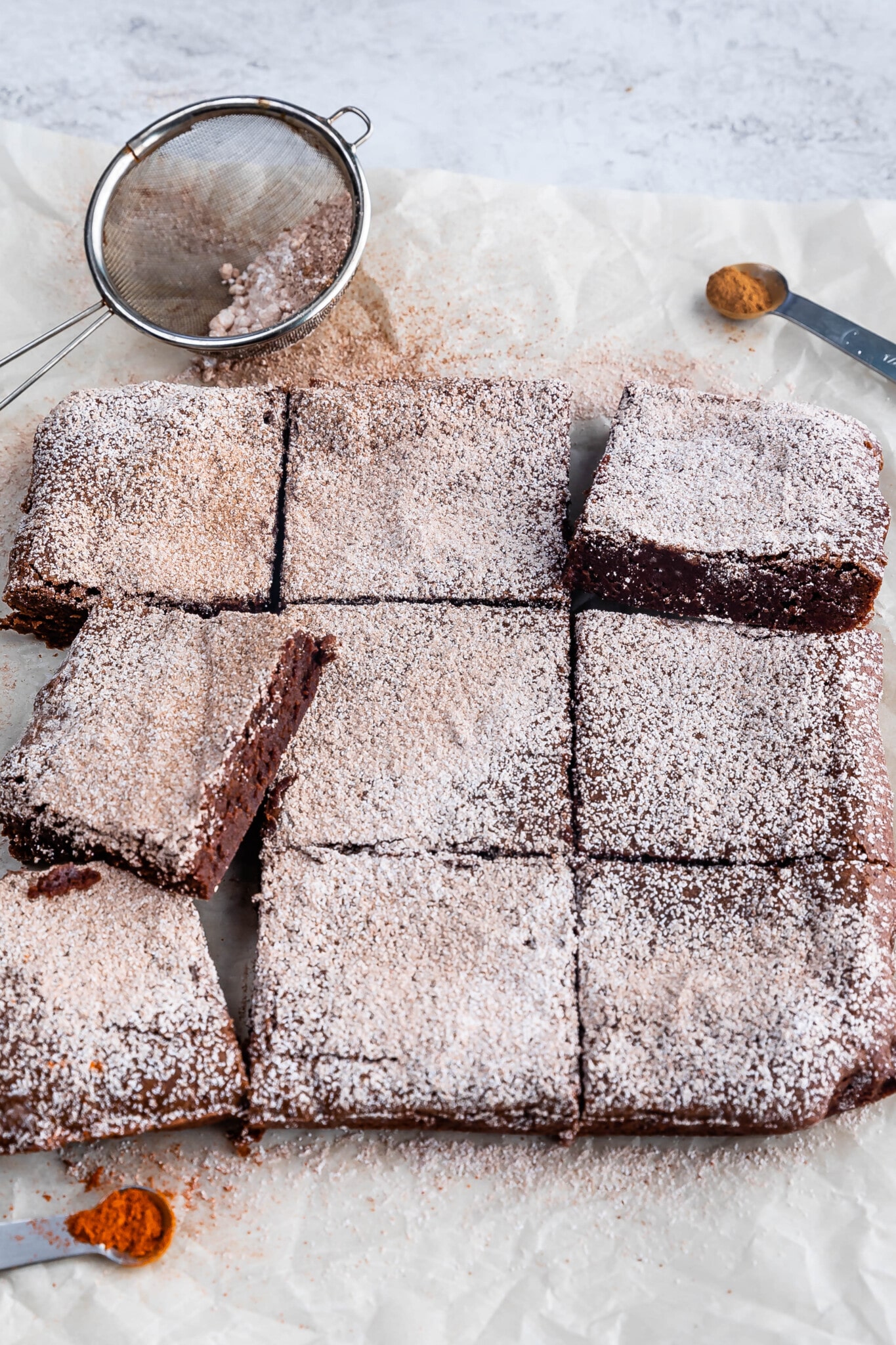 Mexican brownies on parchment with powdered sugar