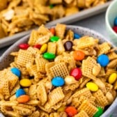 bowl of Chex mix with M&Ms with pan of mix behind