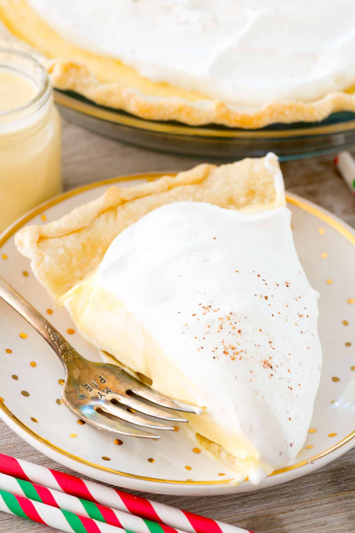 a slice of eggnog pie on a white plate next to a gold fork