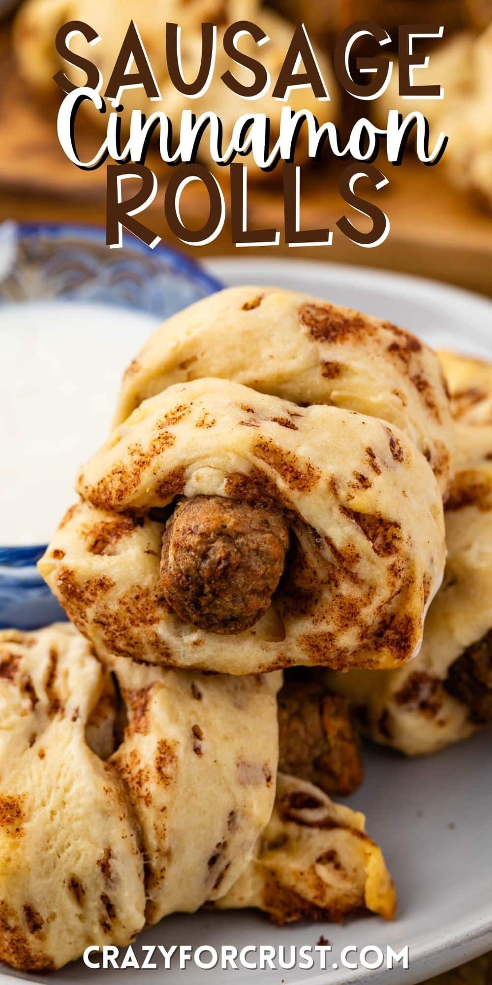 sausage wrapped in cinnamon rolls on a grey plate with words on the image.