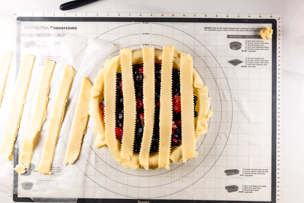 pie with fruit filling topped with vertical strips of pie dough.