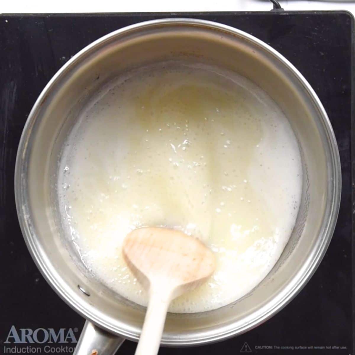 saucepan on hot plate with boiling milk and sugar.