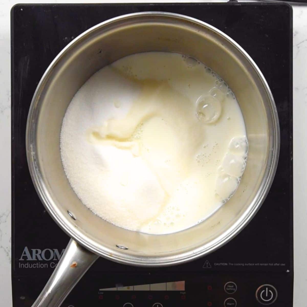 saucepan on hot plate with milk and sugar.