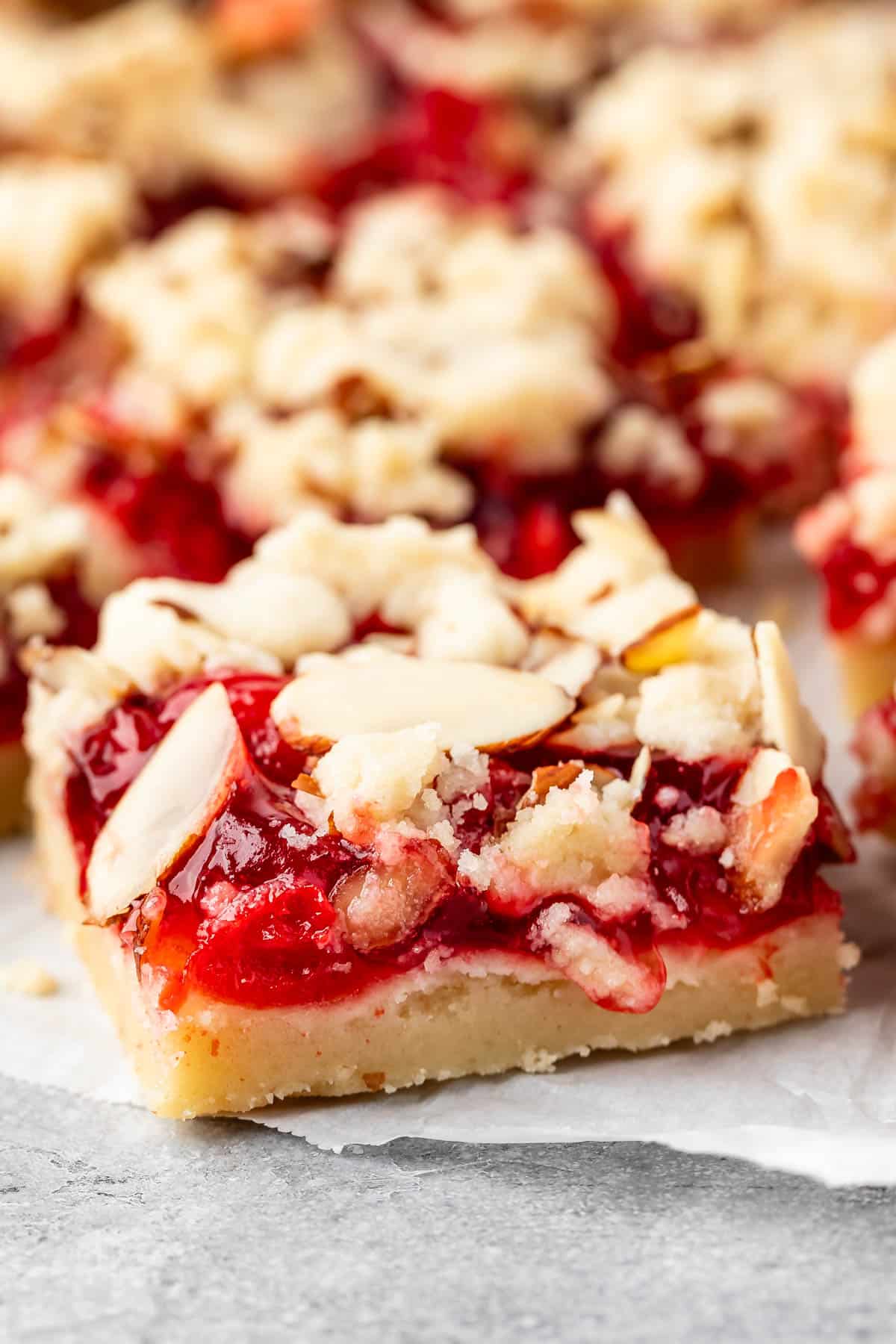pie crust bars with red cherry pie filling and sliced almonds on top.