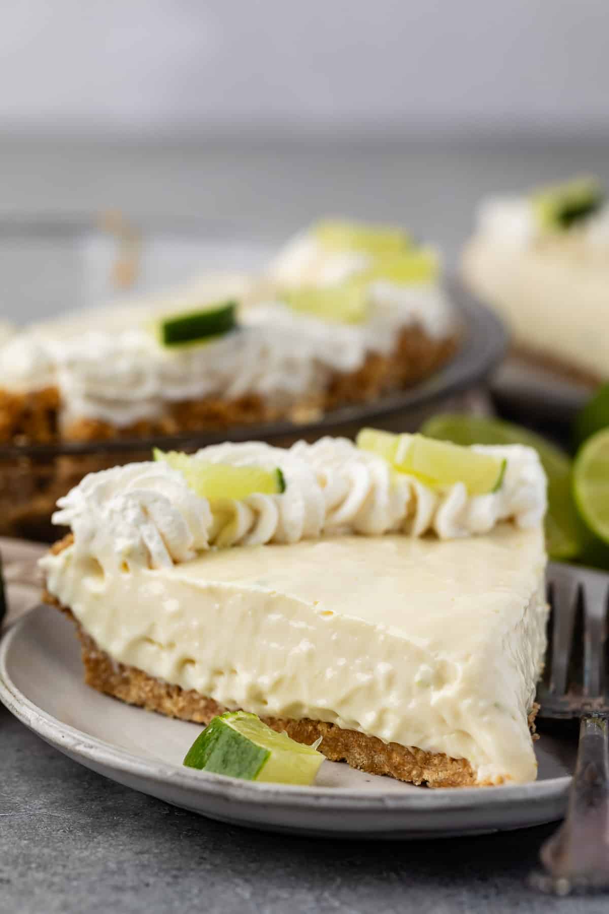 slice of key lime pie with whipped cream and sliced lime on top.