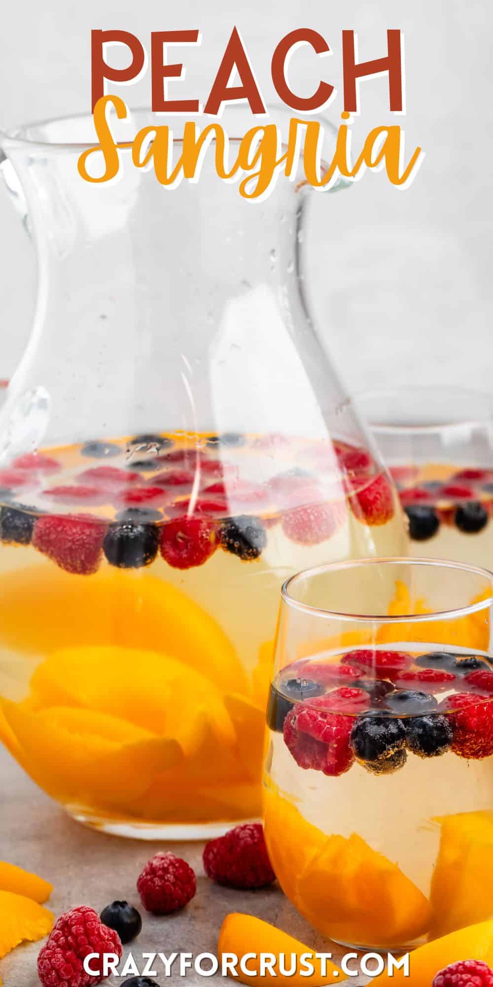 clear glasses holding the clear drink with raspberries, blueberries, and peaches sitting inside with words on the image.