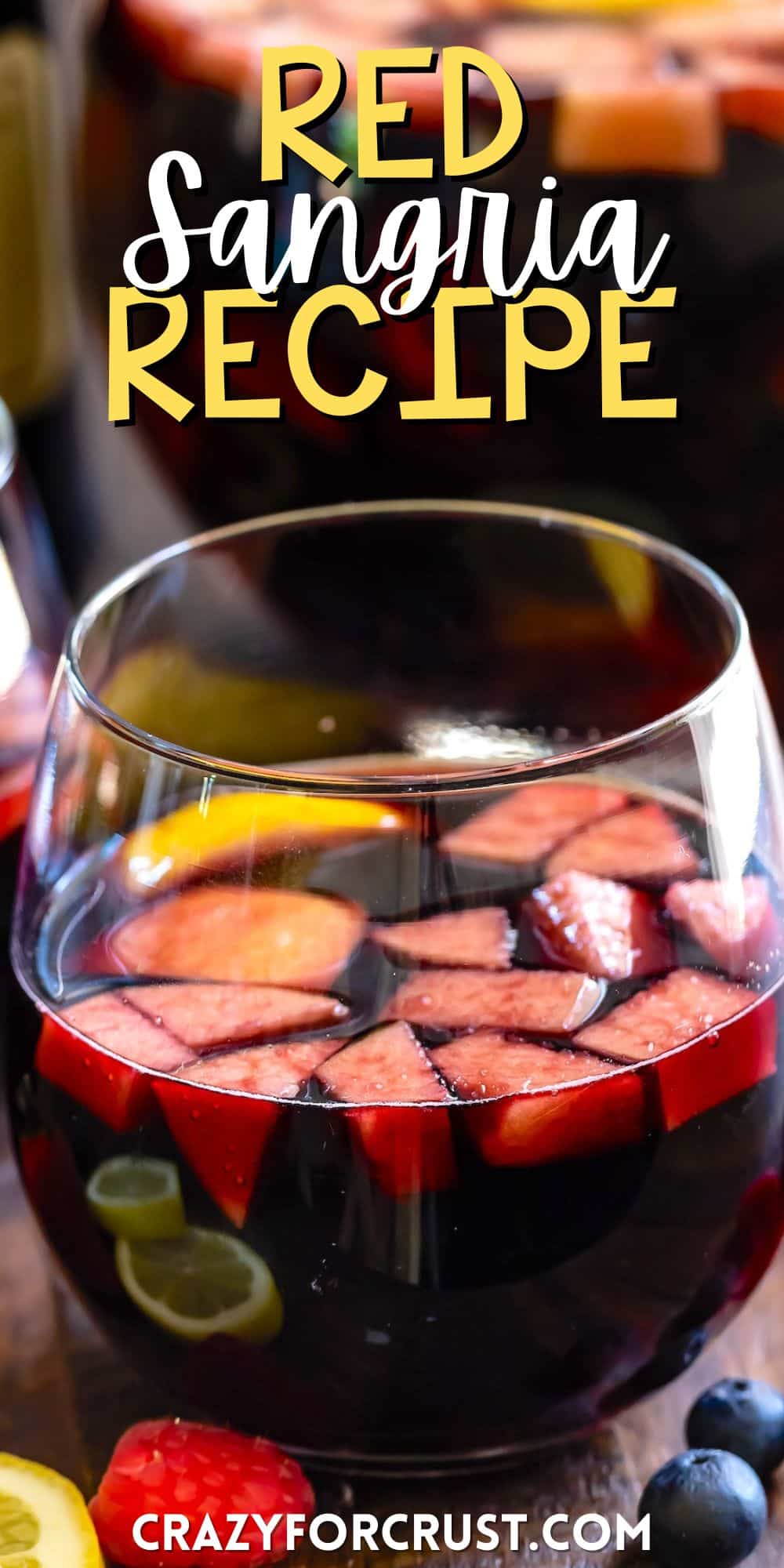 dark red wine in a short clear glass with fruit chopped up inside with words on the image.