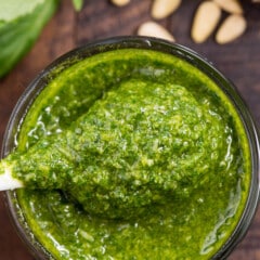 spoon scooping pesto out of a clear jar.