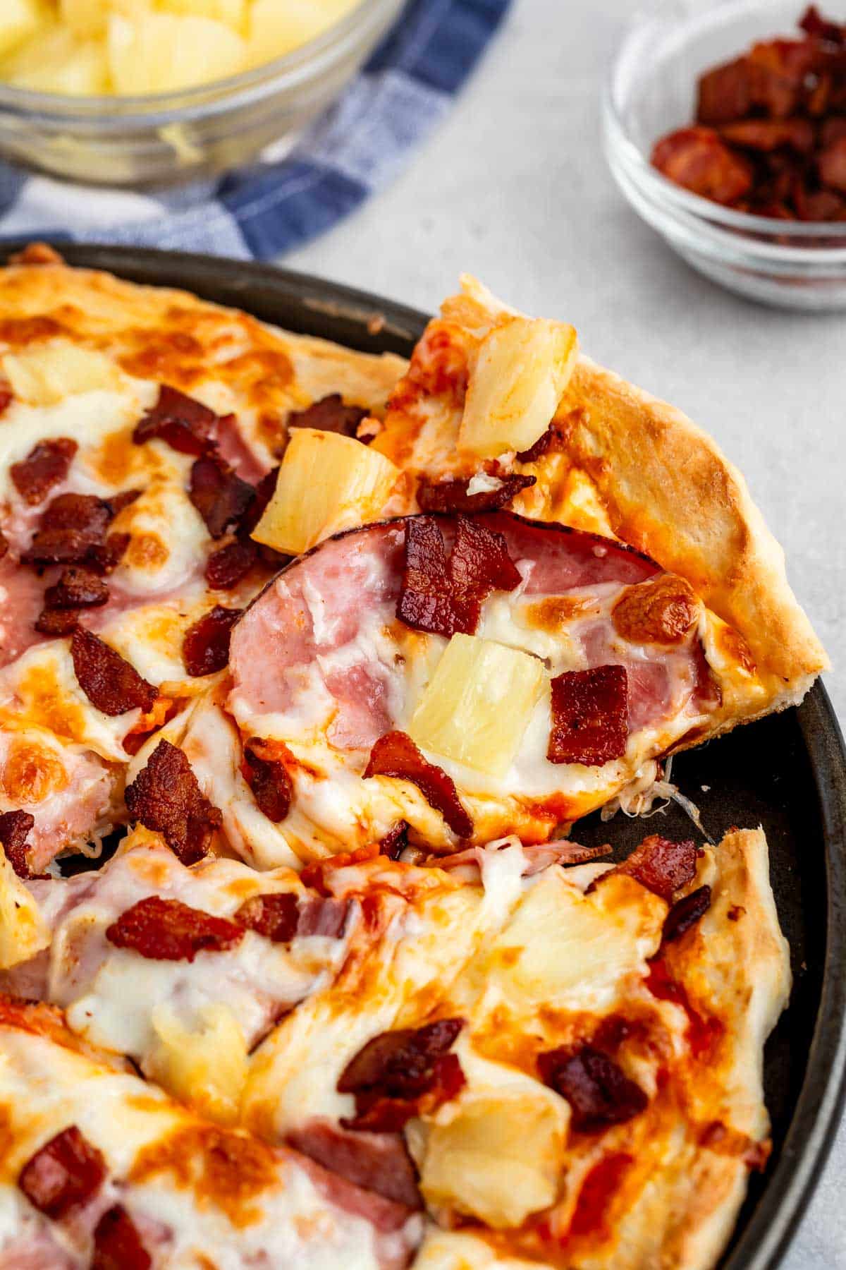 pizza with cheese, pineapple, ham, and bacon on top.
