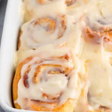 cinnamon rolls sitting in a glass white pan.