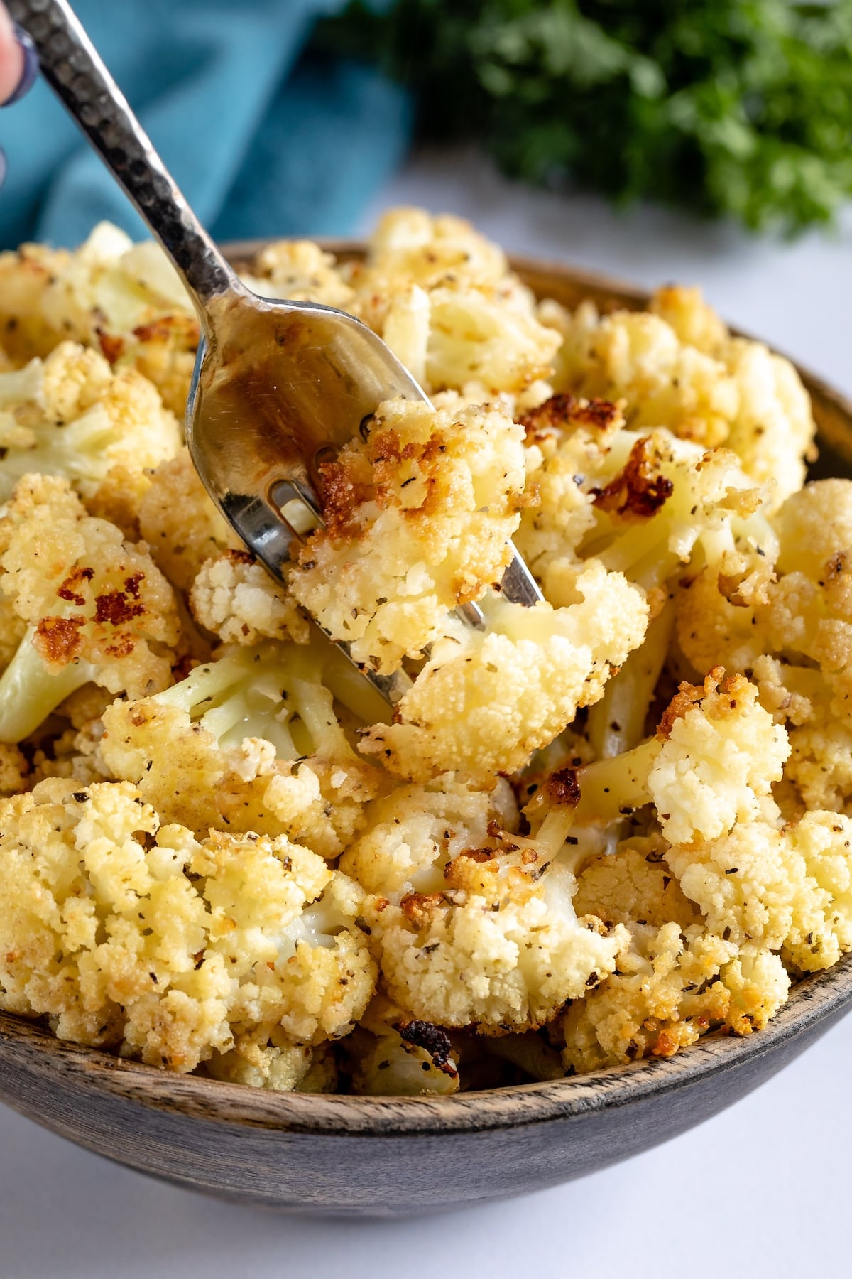 cauliflower in a wood bowl with a fork picking up some pieces.