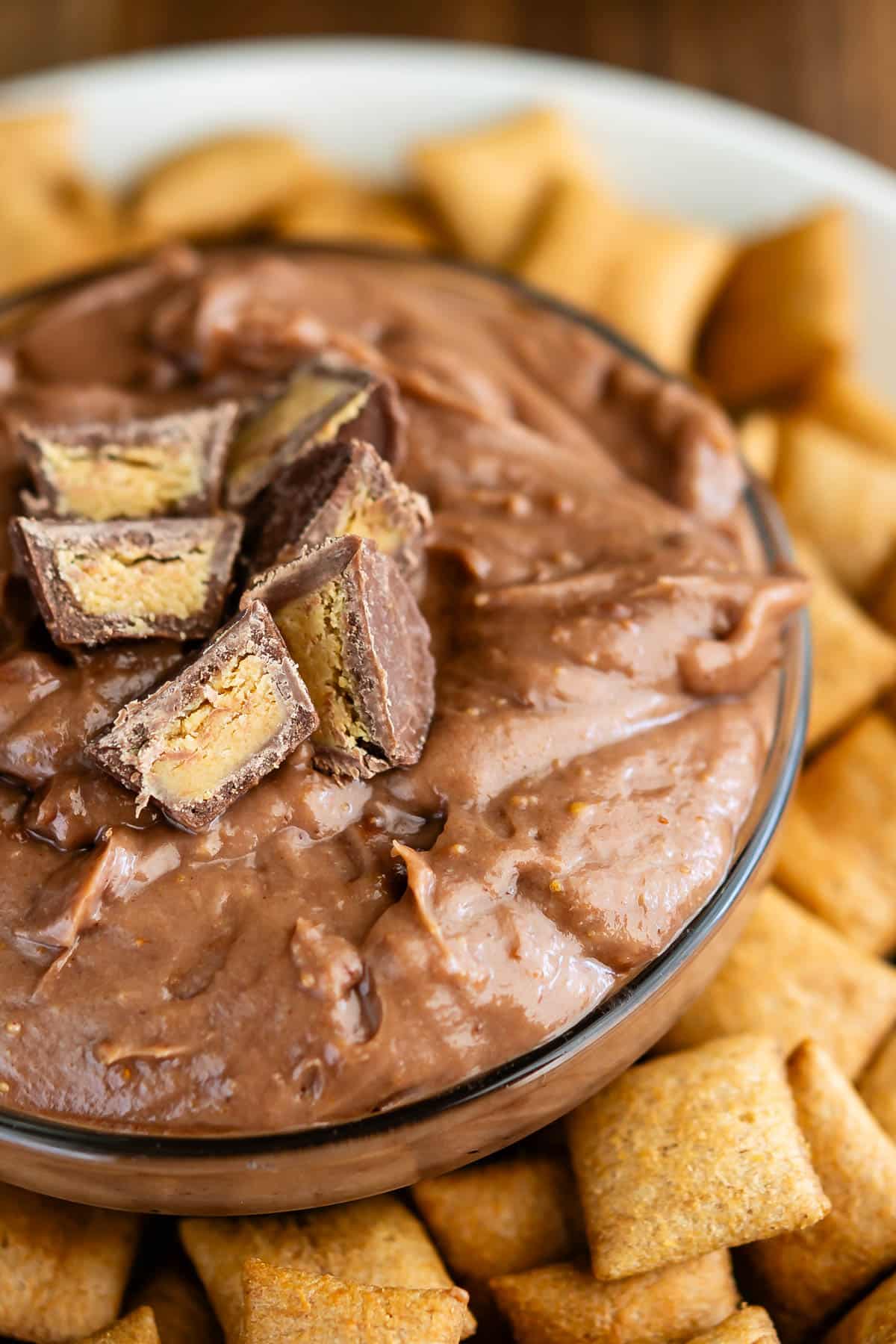 chocolate dip in a clear bowl surrounded by crackers.