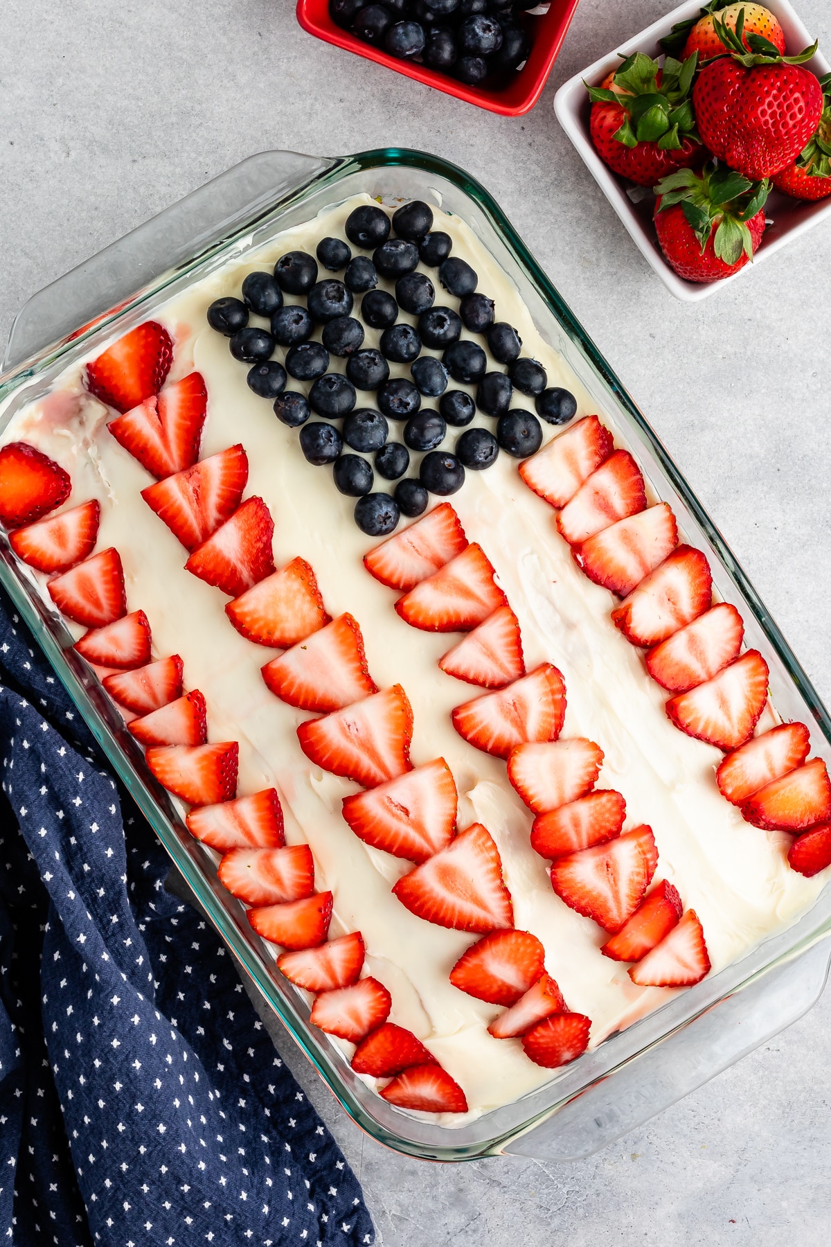 cake with white frosting and sliced strawberry and blueberries on top to make an American flag.