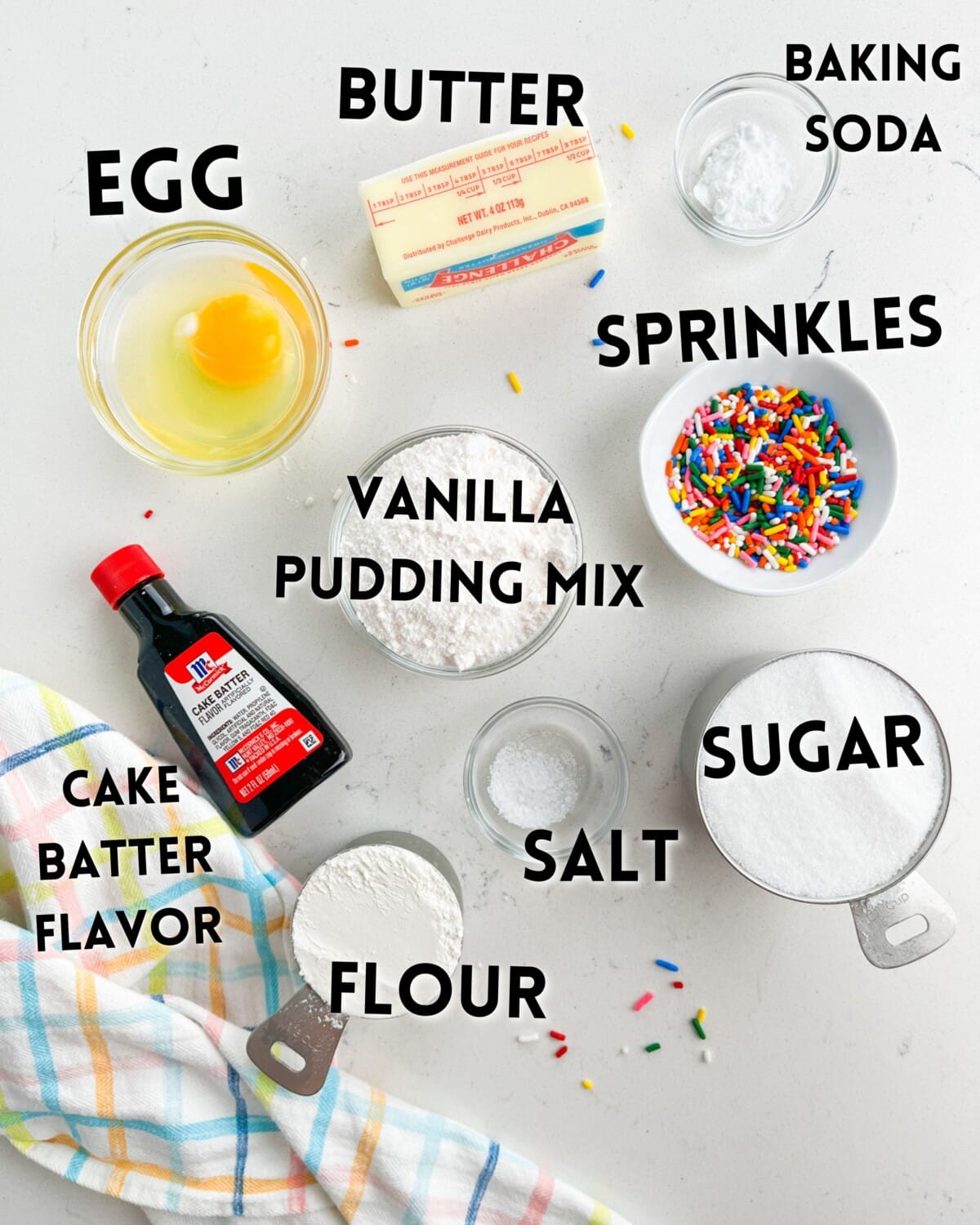 ingredients in funfetti cookies laid out on a white marble counter.