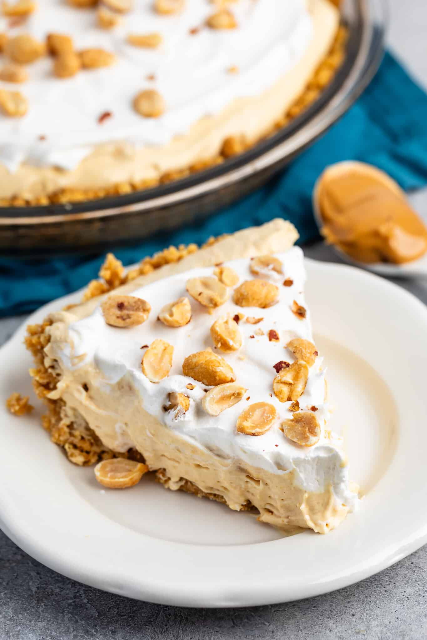 peanut butter pie on a white plate with peanuts on top.