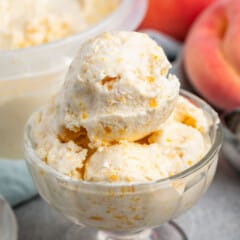 multiple scoops of light orange ice cream in a clear ice cream bowl.