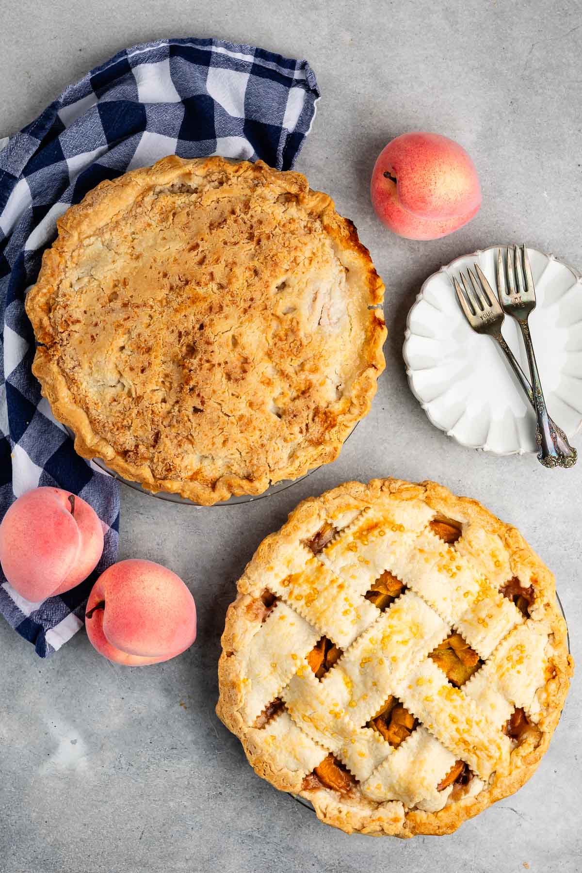 two peach pies with one being crumble topping and the other being lattice topped.