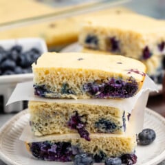 stacked square pancakes with blueberries baked in on a white plate.
